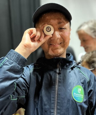 A learner holding an eye prop up against his eye during the touch tour.