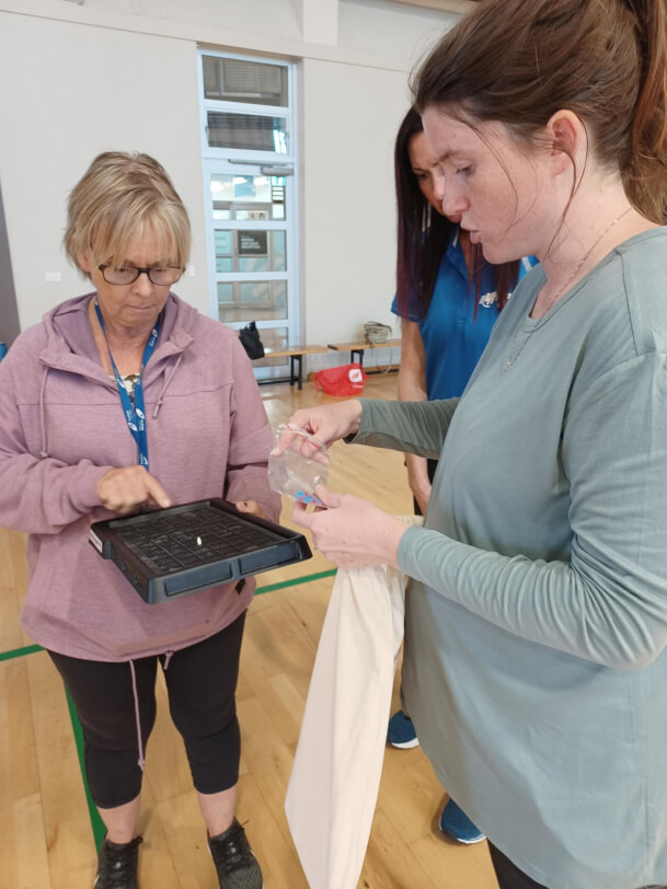 Casey from Blind Sport NZ talking to an RTV who is holding some accessible equipment.