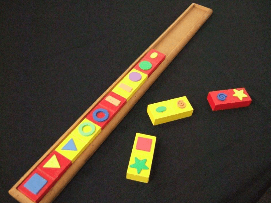 A set of wooden dominoes with tactile shapes and a long wooden tray to fit them into.