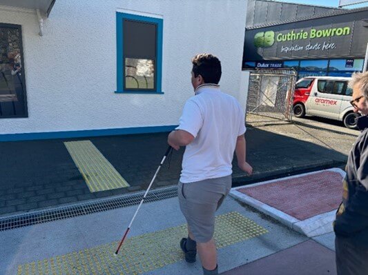 Learner using a cane and hazard dots to cross a street safely