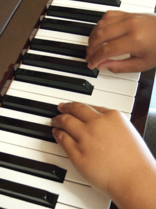 Child’s hands exploring piano keys.